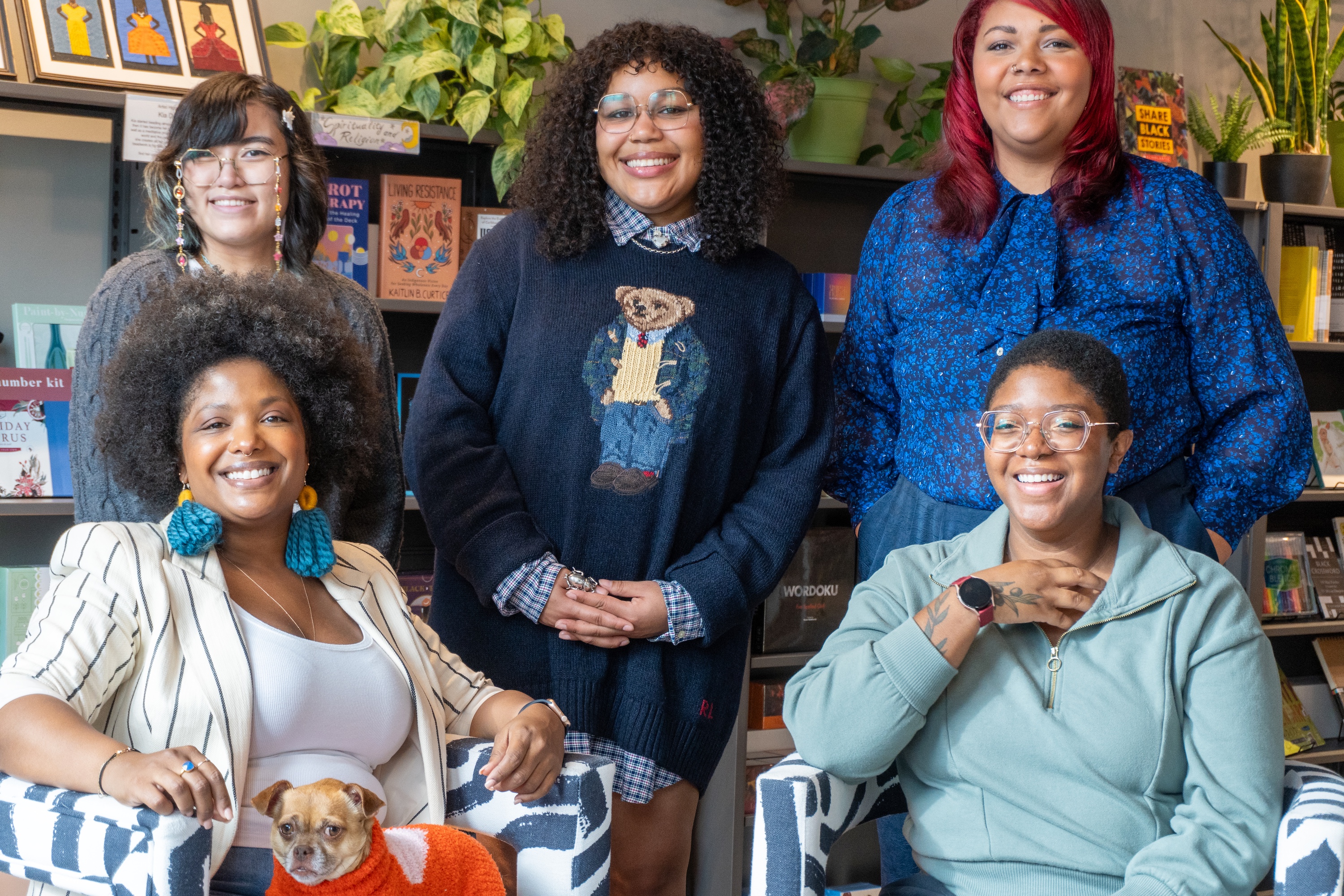 Five Black women who run Black Garnet Books smiling in front of bookshelves.